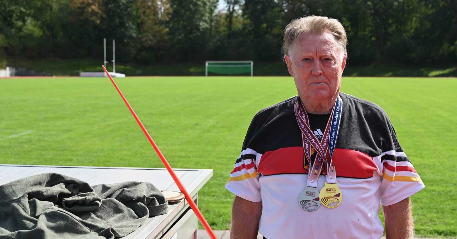 Reiner Görtz im Deutschland-Trikot mit Gold- und Silbermedaille der Masters-WM in Daegu auf dem Sportplatz