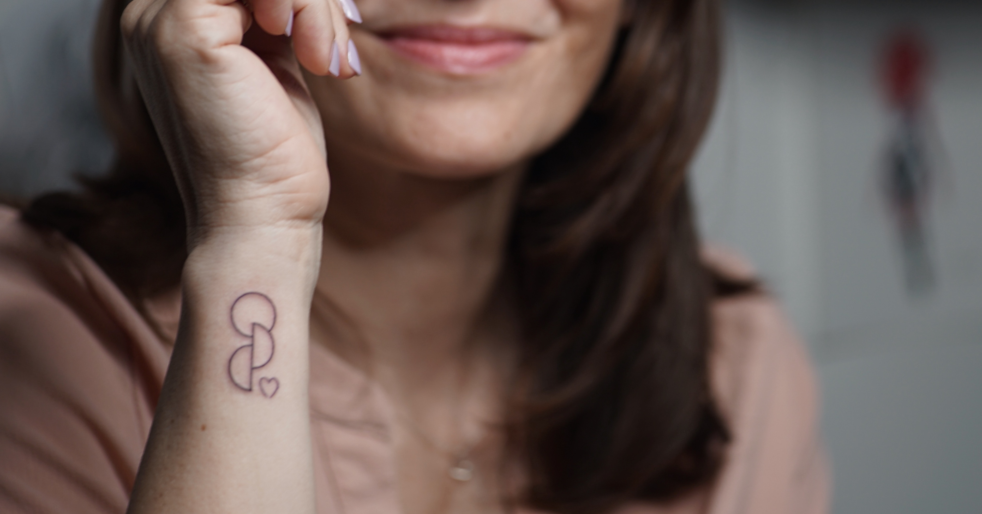 Frau zeigt das kleine Organspende-Tattoo mit Herz an ihrem Handgelenk