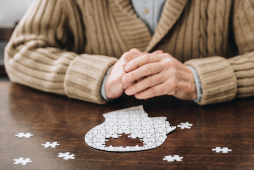 Mann sitzt vor einem Puzzle, das die Form eines Gehirns hat