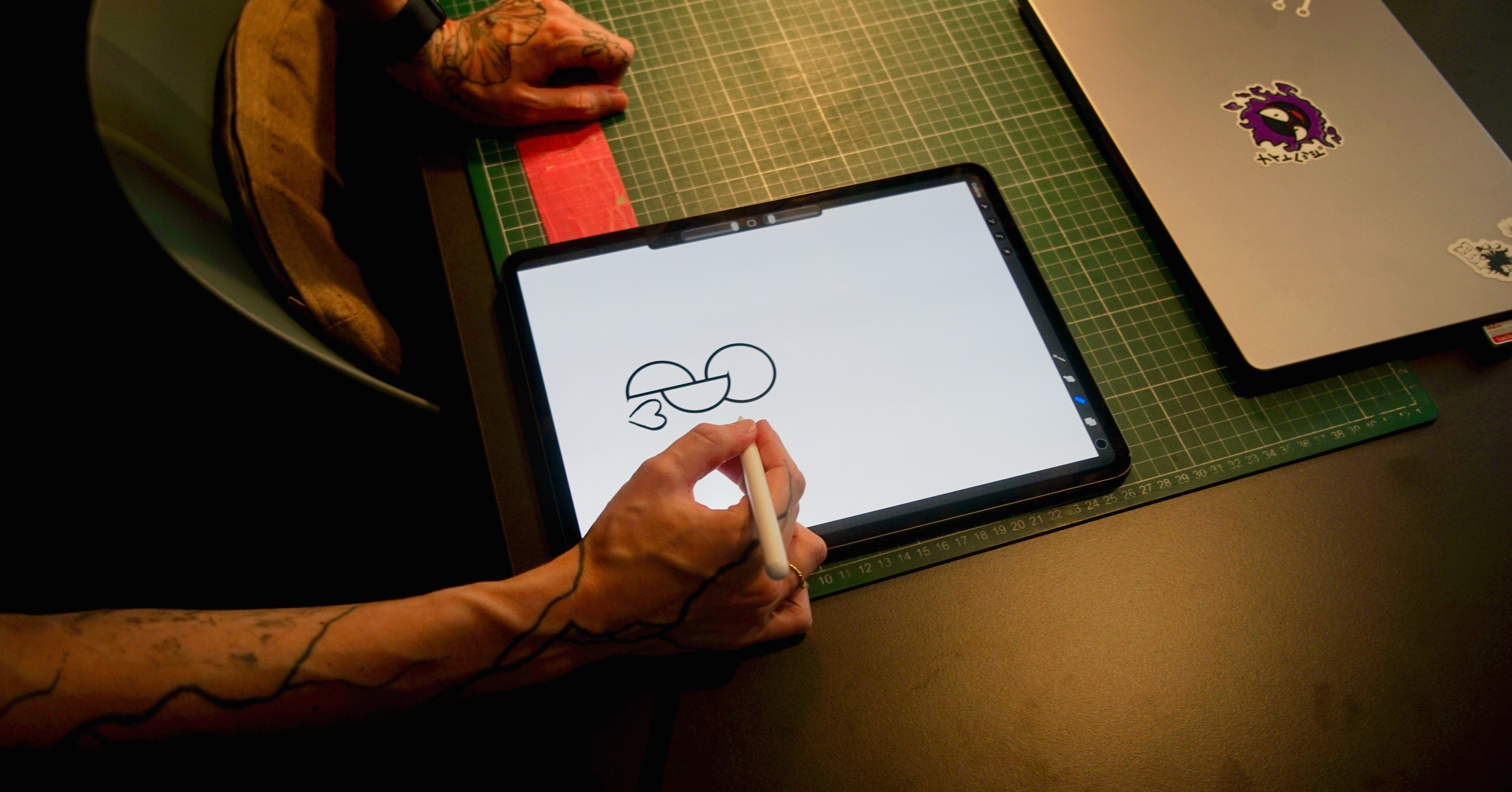 Tätowierte Hand zeichnet das Organspende-Symbol mit kleinem Herz auf einem Tablet