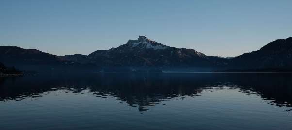 Schneebedeckter Gipfel des Schafbergs spiegelt sich im ruhigen Wasser des Mondsees