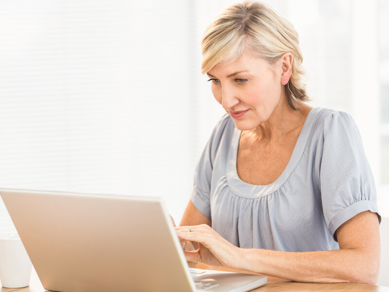 Blonde Frau im mittleren Alter sitzt am Laptop