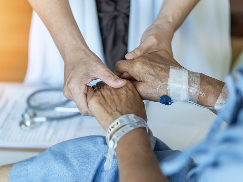 Ärztin hält beide Hände eines Patienten